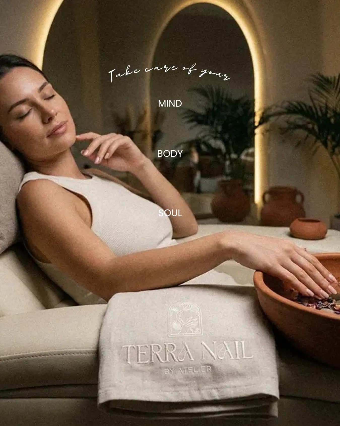 A guest reclining in the pedicure lounge in front of a backlit arch set into the wall