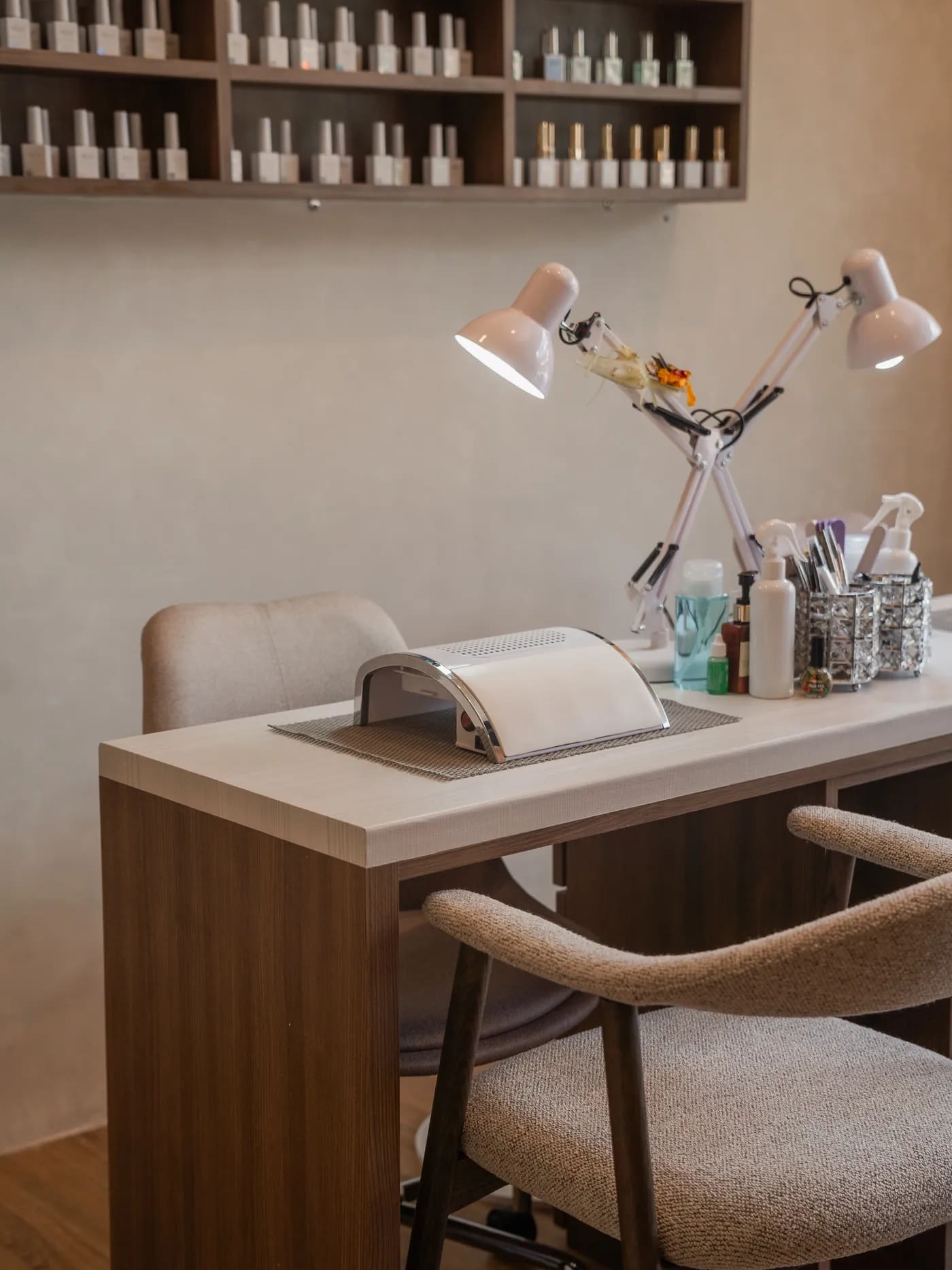 A manicure station at Terra Nail, with a hand rest, lamp and shelves of polish behind